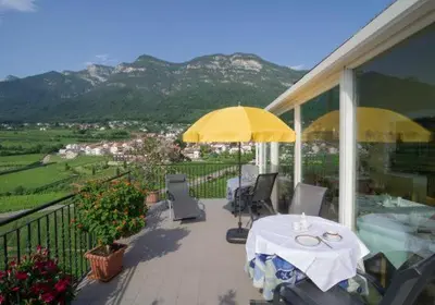 a patio with a table and umbrella on a house at Gästehaus Zugal in Caldaro