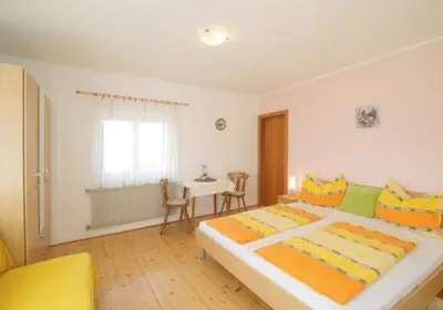 a bedroom with a large bed and a table at Gästehaus Zugal in Caldaro