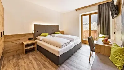 a bedroom with a bed and a large window at Hotel Garni Sonngart in Andrian