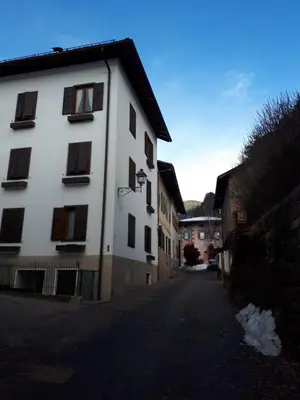 a white building with black windows on a street at Riccarden Cavalese Centro in Cavalese