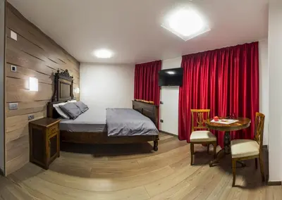 a bedroom with a bed and a table and red curtains at NonSoloMele in Romallo