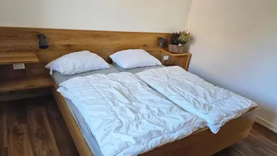 a bed with a wooden head board and two pillows at Panorama Dolomiti in San Vigilio Di Marebbe