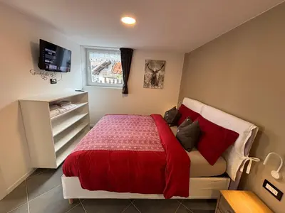 a bedroom with a bed with a red blanket at Casa dei BROCA - Cavalese Val di Fiemme in Cavalese