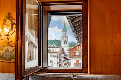 a window with a view of a church at Dolympic View Cortina in Cortina dʼAmpezzo