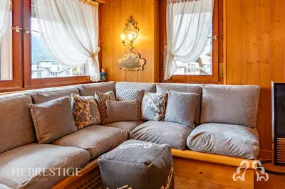 a brown couch in a living room with windows at Dolympic View Cortina in Cortina dʼAmpezzo