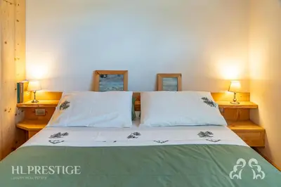 a bedroom with a bed with two lamps on two tables at Dimora del Corso Cortina in Cortina dʼAmpezzo