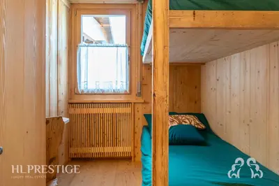 a bunk bed in a wooden room with a window at Dimora del Corso Cortina in Cortina dʼAmpezzo