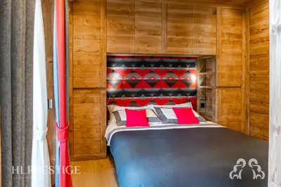 a bed with red pillows in a wooden room at Alpenglow Cortina Luxury in Cortina dʼAmpezzo