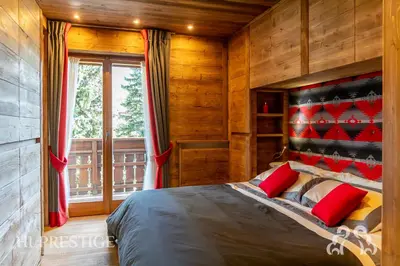 a bedroom with a bed with red pillows and a window at Alpenglow Cortina Luxury in Cortina dʼAmpezzo