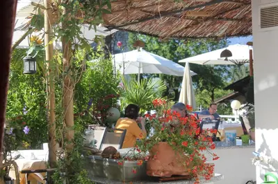 a group of people sitting at a table under an umbrella at Hotel Annabell in Merano