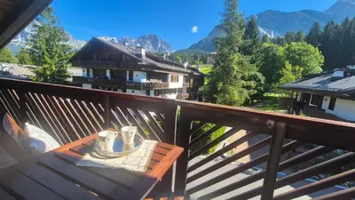 a wooden balcony with a table with cups on it at Apartment 5 Torri, parcheggio in garage in Cortina dʼAmpezzo