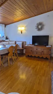 a living room with a table and a large television at Apartment 5 Torri, parcheggio in garage in Cortina dʼAmpezzo