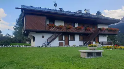 a house with a balcony with flowers in a yard at Apartment 5 Torri, parcheggio in garage in Cortina dʼAmpezzo