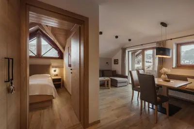 a bedroom with a bed and a dining room with a table at ELMA Corvara in Corvara in Badia