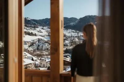a woman looking out of a window at a city at ELMA Corvara in Corvara in Badia