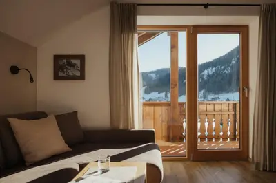 a living room with a couch and a sliding glass door at ELMA Corvara in Corvara in Badia