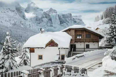 a house covered in snow with mountains in the background at ELMA Corvara in Corvara in Badia