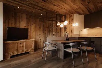 a kitchen with a table with chairs and a television at ELMA Corvara in Corvara in Badia