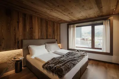 a bedroom with a bed with a large window at ELMA Corvara in Corvara in Badia