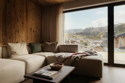 a living room with a couch and a large window at ELMA Corvara in Corvara in Badia