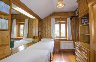 two beds in a room with wooden walls and windows at Casa Alpina centrale con vista sulle Dolomiti in Cortina dʼAmpezzo