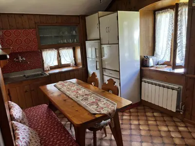 a kitchen with a wooden table and a refrigerator at Casa Alpina centrale con vista sulle Dolomiti in Cortina dʼAmpezzo