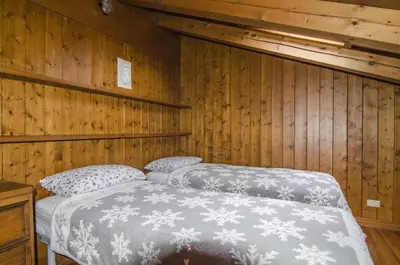 two beds in a room with wooden walls at Comfort a due passi dal centro in Cortina dʼAmpezzo