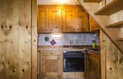 a kitchen with wooden cabinets and a stove at Comfort a due passi dal centro in Cortina dʼAmpezzo