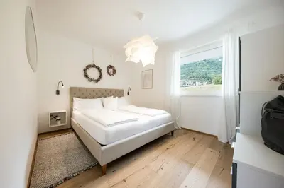 a white bedroom with a bed and a window at Panorama Apartment in Nalles