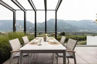 a white table with chairs and a view of mountains at Panorama Apartment in Nalles