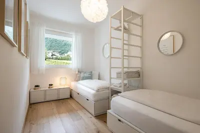 a bedroom with a bed and a shelf and a window at Panorama Apartment in Nalles