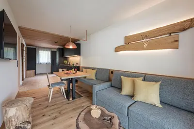 a living room with a blue couch and a table at Knöspele - Brennerei & Genuss-Apartments in Brixen