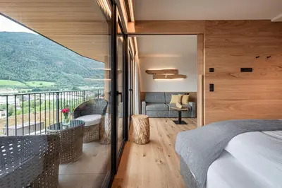 a balcony with wicker chairs and a table with a view at Knöspele - Brennerei & Genuss-Apartments in Brixen