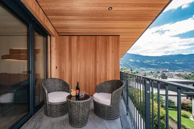 a bedroom with a white bed with a wooden headboard at Knöspele - Brennerei & Genuss-Apartments in Brixen