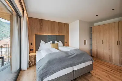 a bedroom with a large bed and a large window at Knöspele - Brennerei & Genuss-Apartments in Brixen