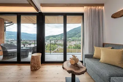 a living room with a couch and a large window at Knöspele - Brennerei & Genuss-Apartments in Brixen