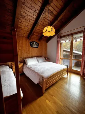 a bedroom with a large bed and a chandelier at La Tana di Giò in Forno di Zoldo