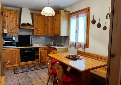 a kitchen with wooden cabinets and a wooden table at La Tana di Giò in Forno di Zoldo