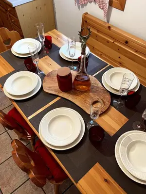 a wooden table with plates and wine glasses on it at La Tana di Giò in Forno di Zoldo