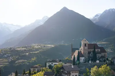 a church on a hill with a mountain in the background at Apartment Prairerhof in Schenna