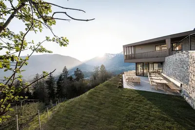 a house on a hill with mountains in the background at Florerhof in Schenna