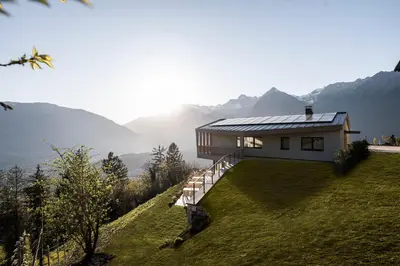 a house on a hill with mountains in the background at Florerhof in Schenna