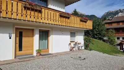 a house with a balcony with a table and a chair at Apartments Angela in San Vigilio Di Marebbe