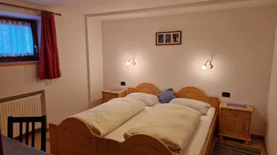 a bedroom with two beds and two lights on the wall at Apartments Angela in San Vigilio Di Marebbe