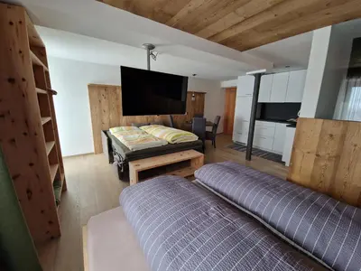 a living room with a tv and a bed and a couch at Apartments Angela in San Vigilio Di Marebbe