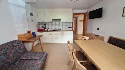 a living room with a table and a kitchen at Apartments Angela in San Vigilio Di Marebbe