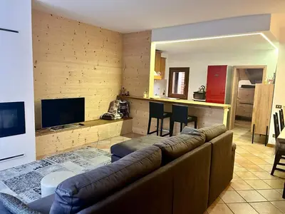a living room with a brown couch and a kitchen at Relax & Elegance apartment near Cortina in San Vito di Cadore
