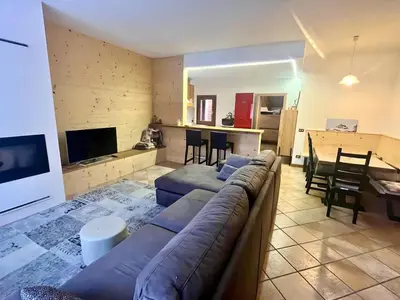 a living room with a couch and a table and a kitchen at Relax & Elegance apartment near Cortina in San Vito di Cadore