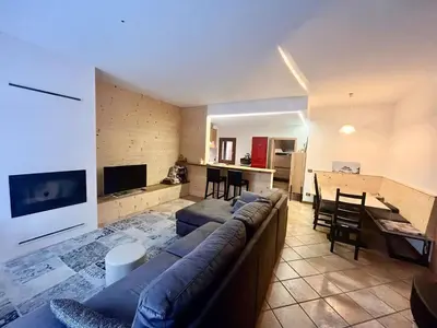 a living room with a large couch and a kitchen at Relax & Elegance apartment near Cortina in San Vito di Cadore
