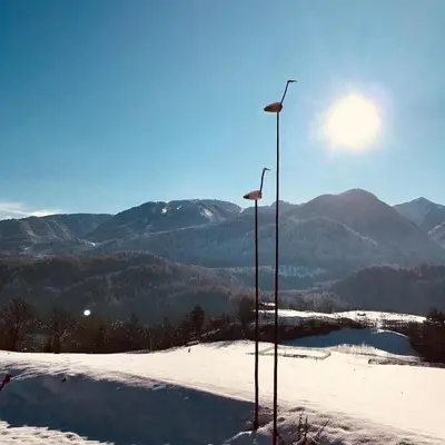 two street lights in the snow next to a body of water at Apartament Loft Fiemme in Castello di Fiemme